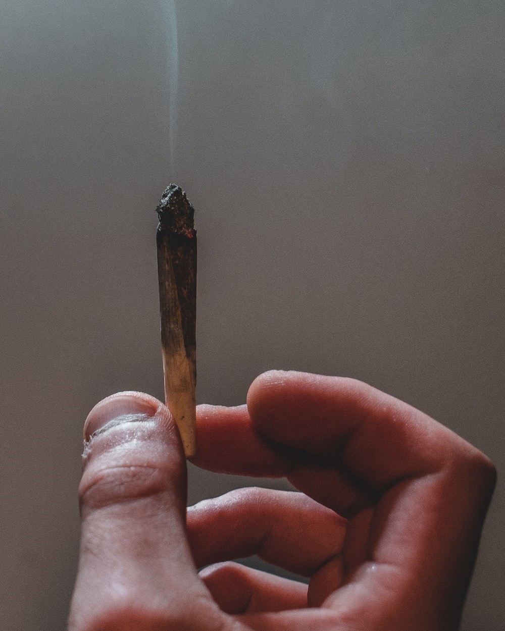 A hand holding a lit up joint