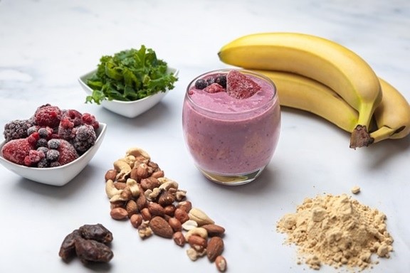 A healthy berry and banana smoothie with protein, vegetables, nuts, and dates.