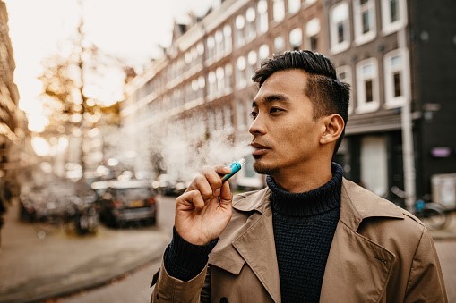 A man vaping in the street.