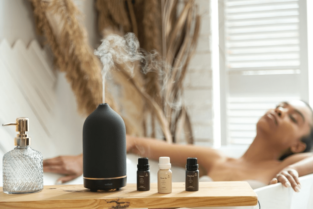 A woman relaxing while taking a bath next to a bottle of essential oil as part of aromatherapy