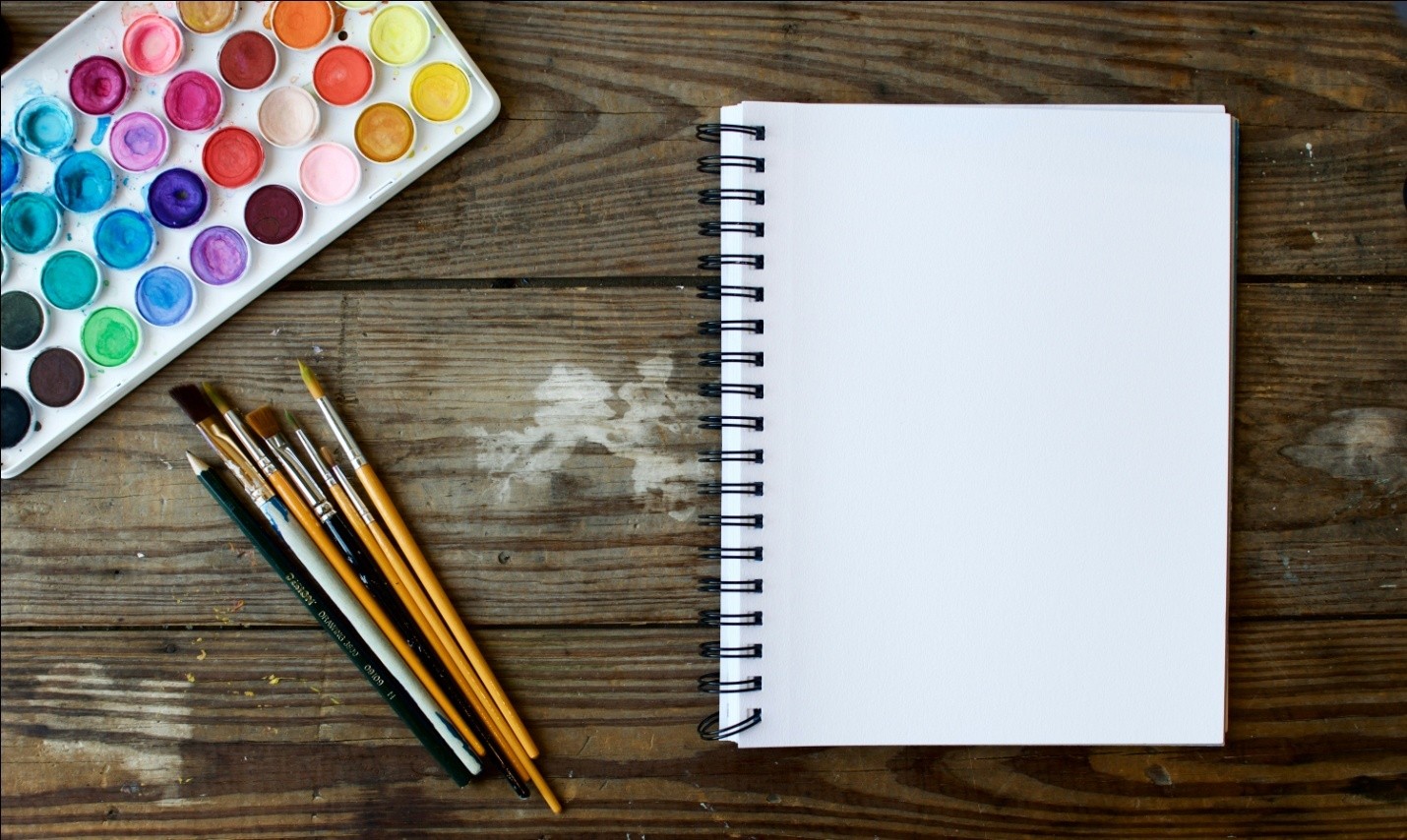 a blank drawing book, a palette, and some paintbrushes