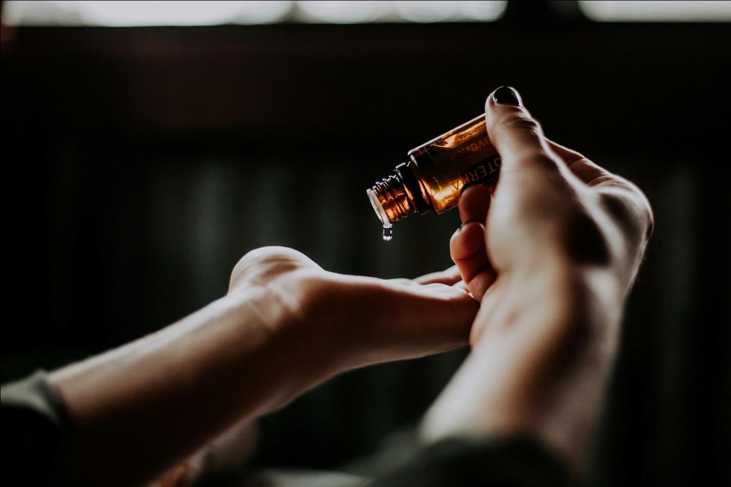 hands pouring contents of amber glass bottle