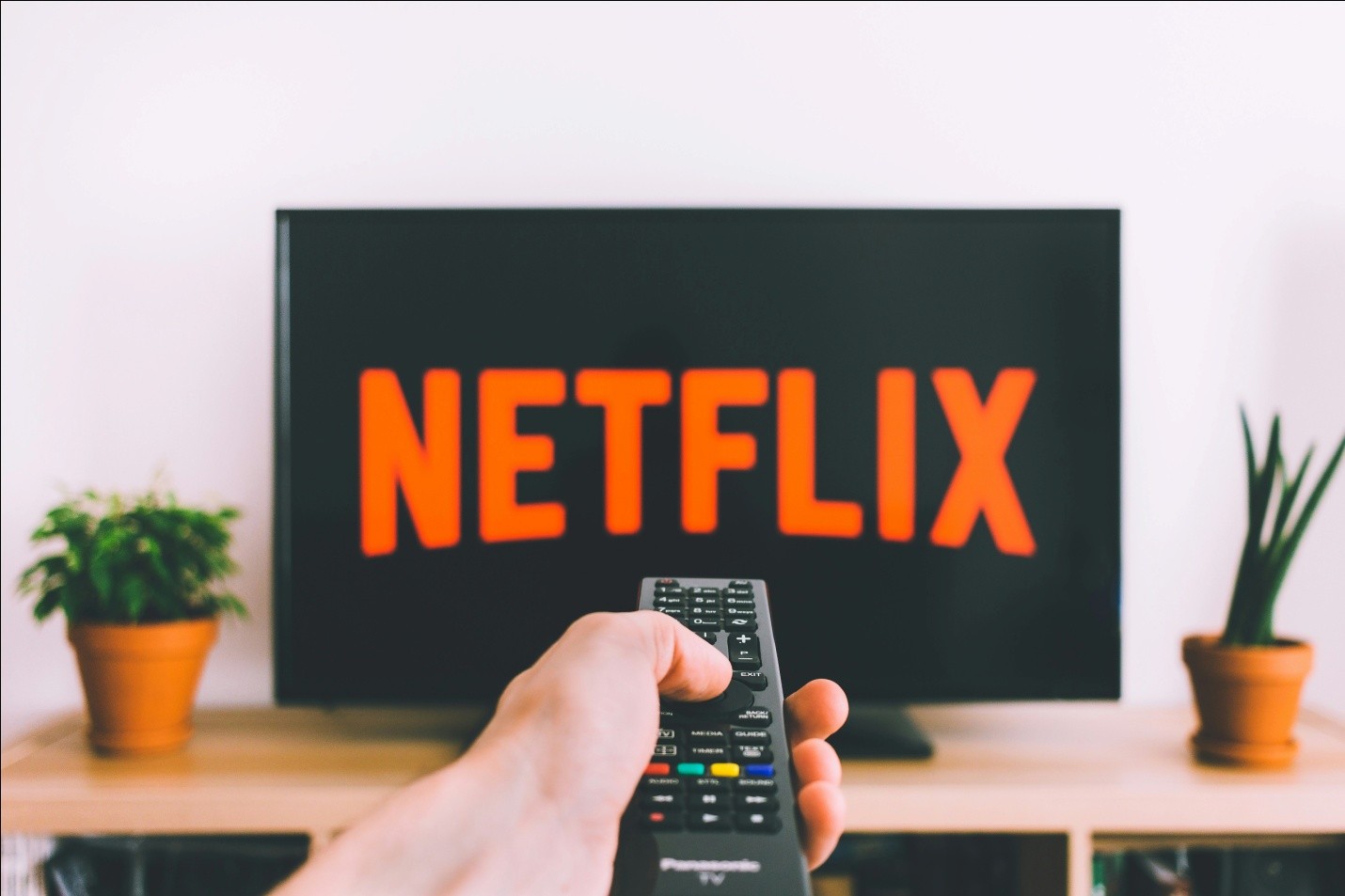 a hand pointing remote towards TV