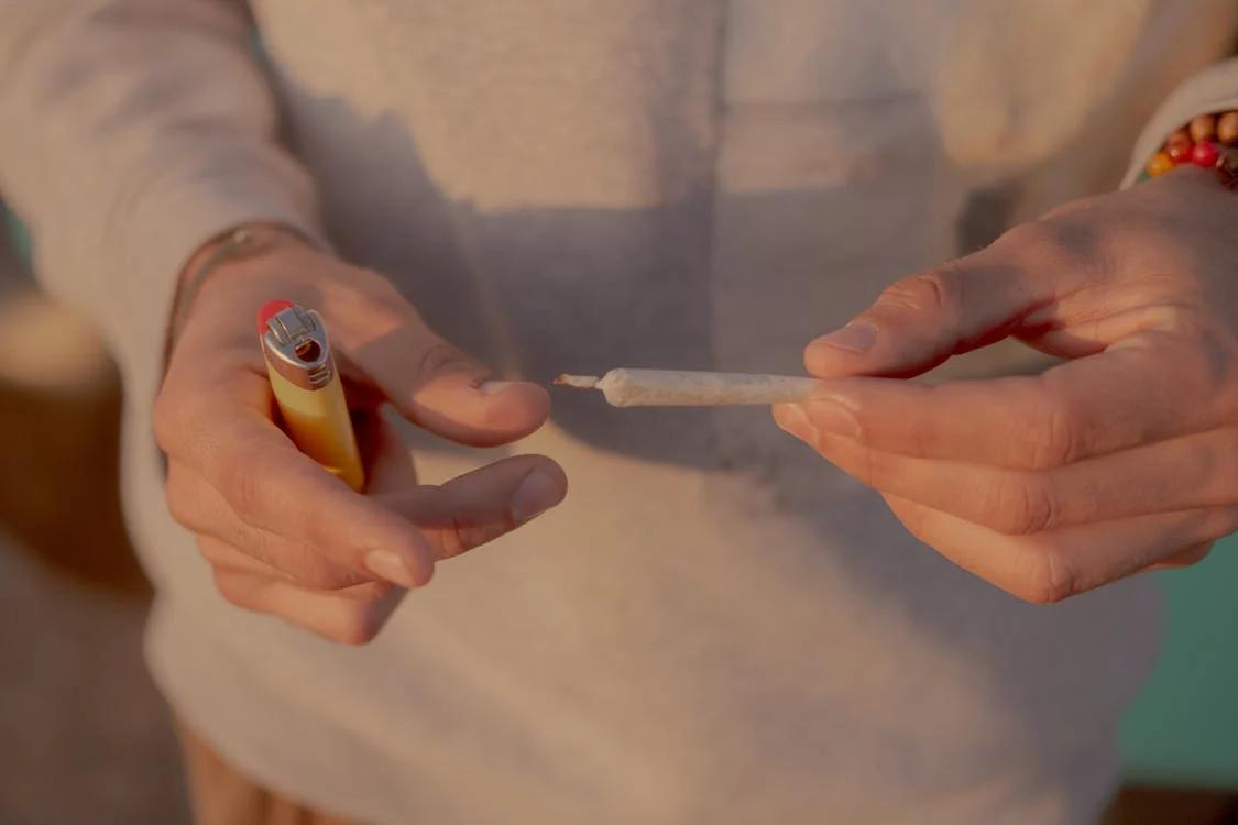 A man holding a blunt and a lighter