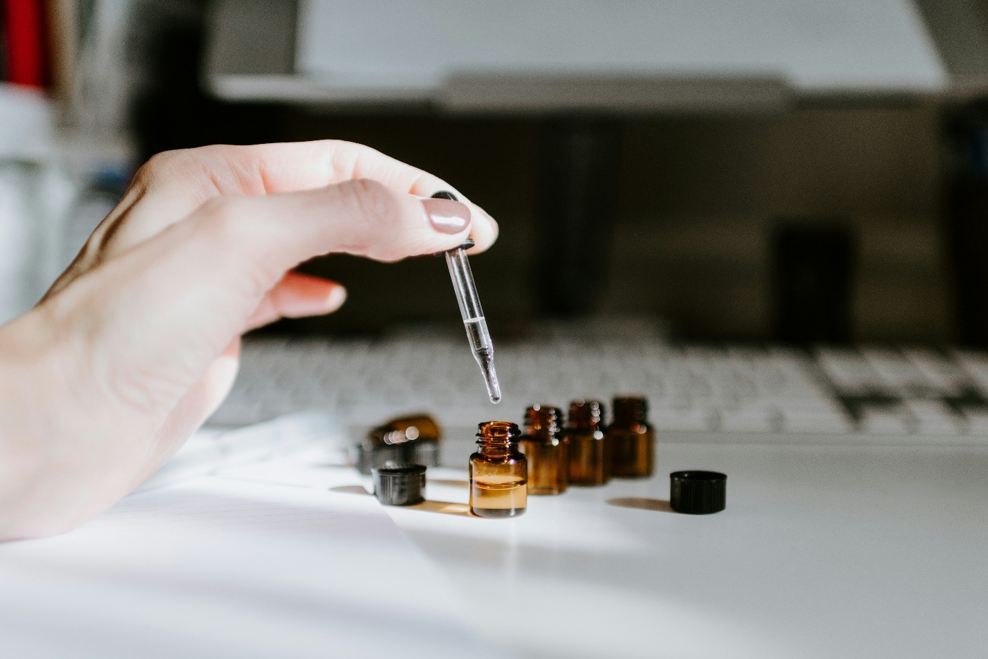 a hand holding a dropper over a small amber bottle