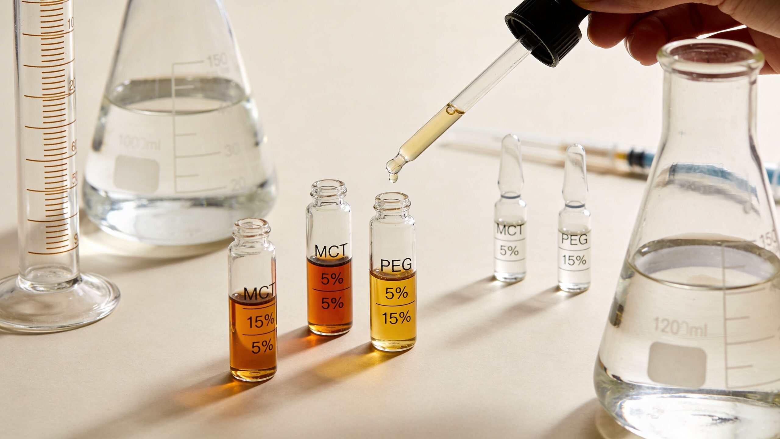 A scientist uses a pipette to fill small glass vials labeled with percentages in a chemistry laboratory.