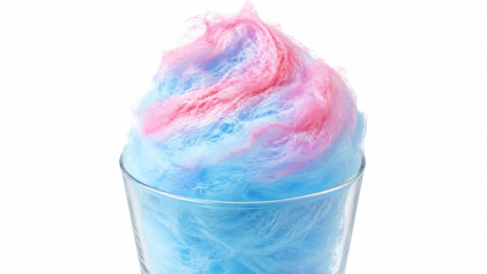 A fluffy pile of pink and blue cotton candy served inside a clear glass cup isolated white.